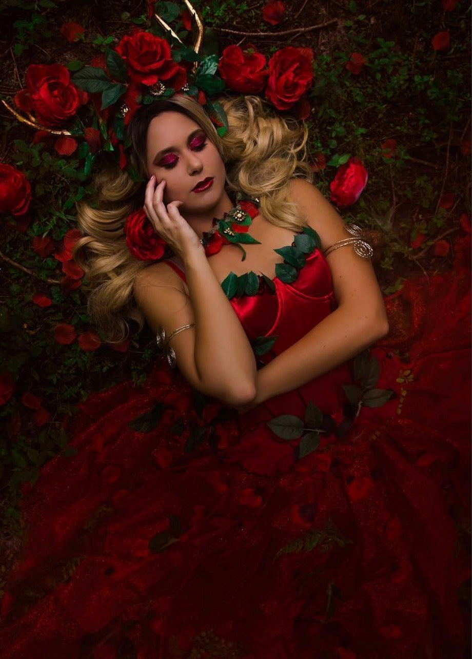BLONDE FAIRY HAIR Woman lying on a bed of red roses with a dark, textured background